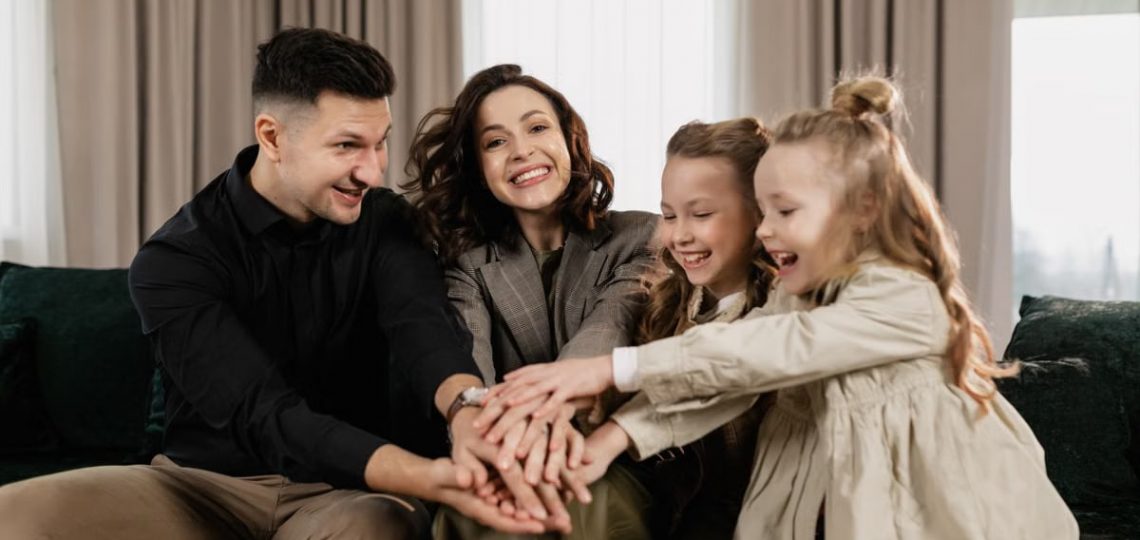 A cheerful family of four bonding together indoors with smiles and joy.
